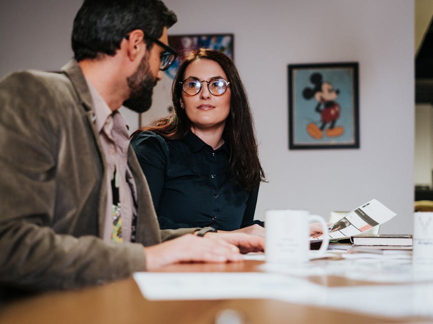 Two colleagues discussing work over coffee in a modern office setting, focusing on collaboration and teamwork.
